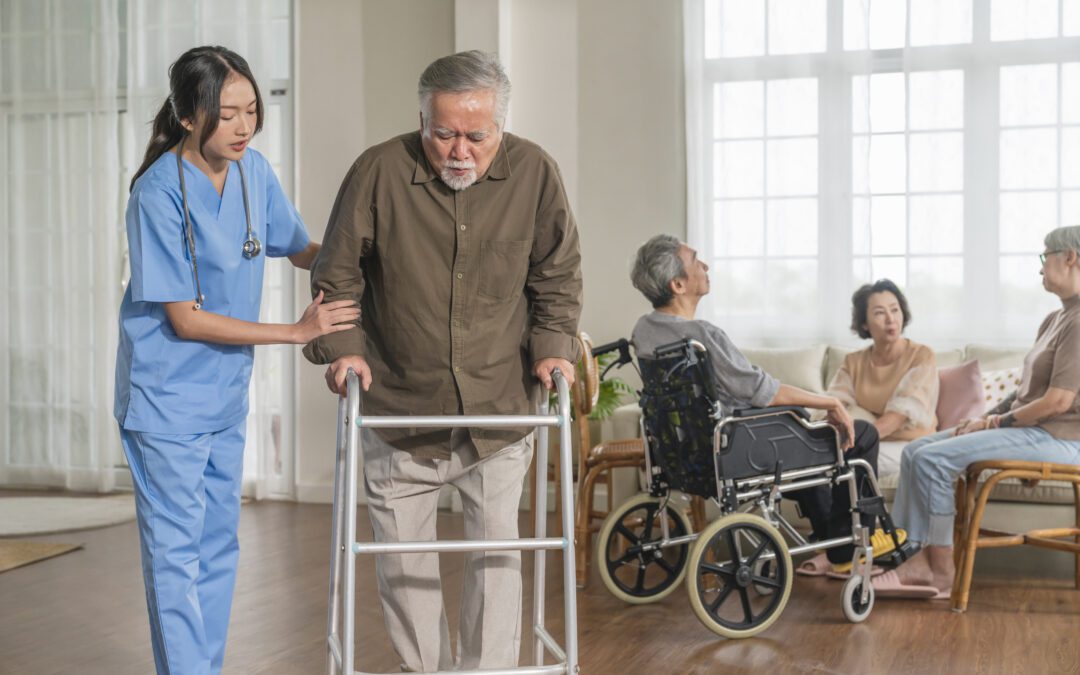 Enfermera asistiendo a un anciano con andador en una residencia de mayores, representando la importancia de los gerocultores y cuidadores en el sector sociosanitario.